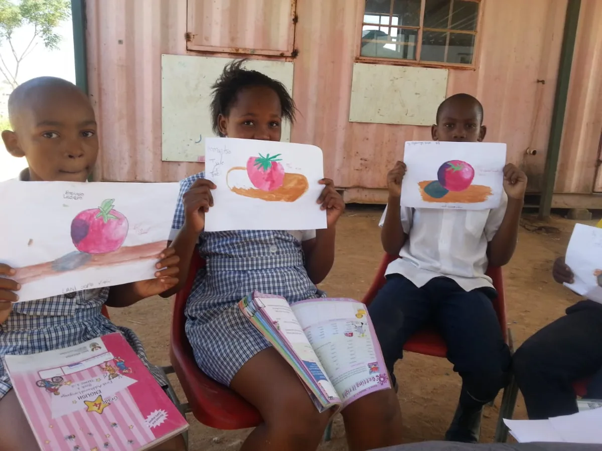 Children holding up their fruit paintings