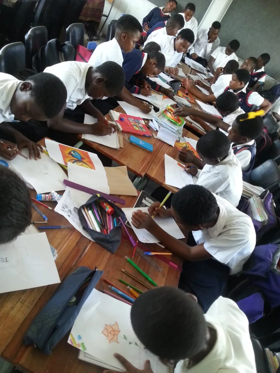 Learners drawing together at long desks