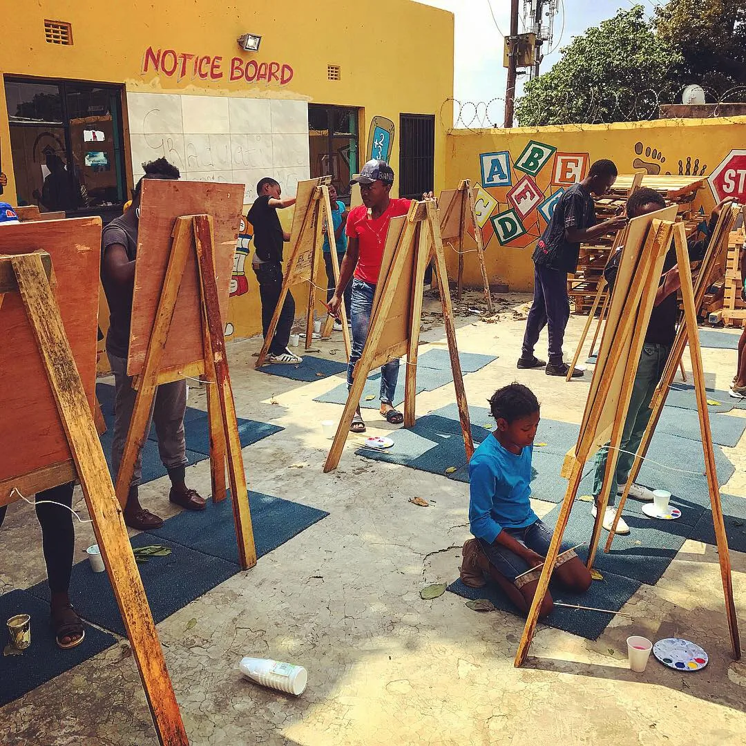 Learners painting at easels in a schoolyard