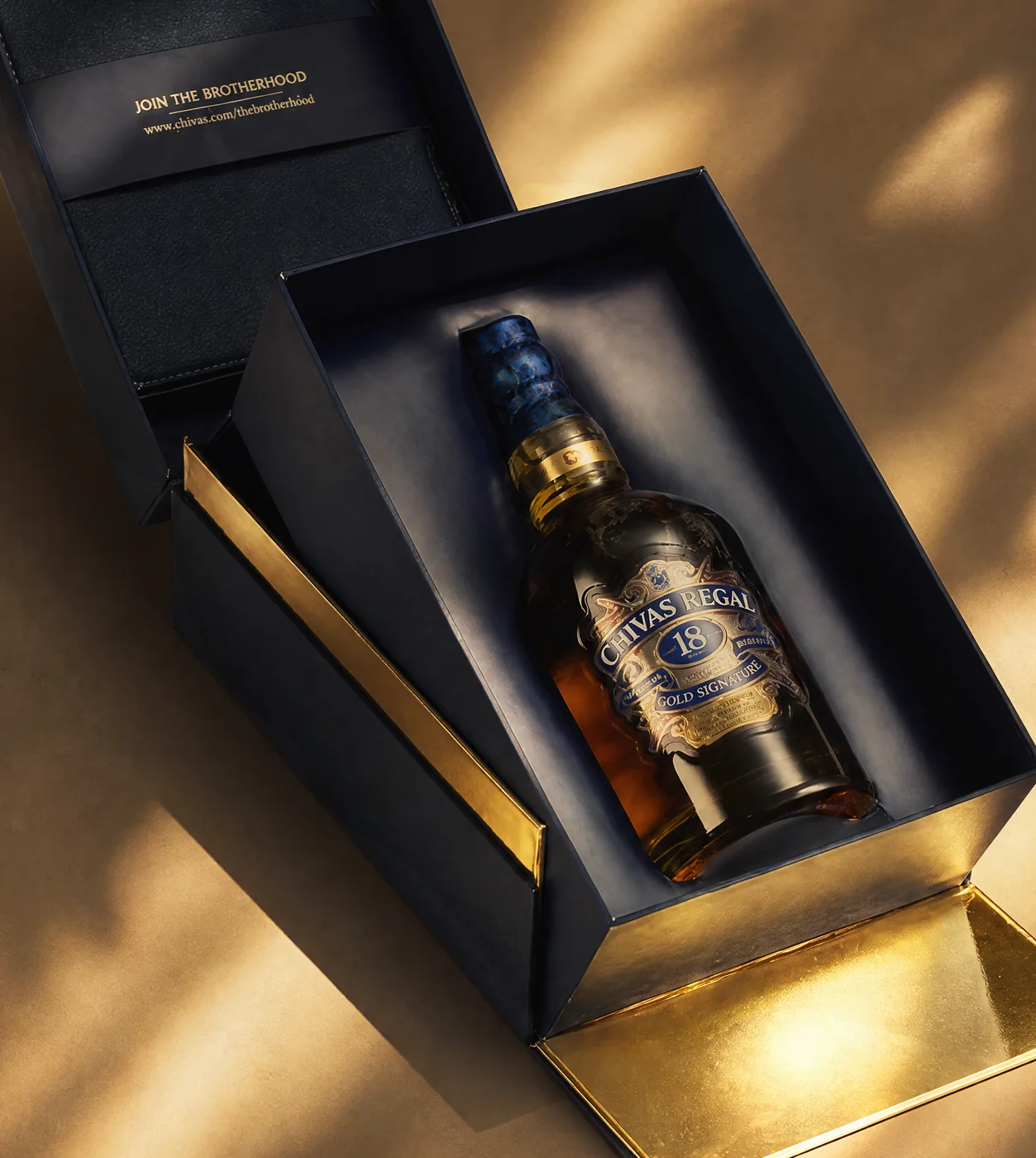 Open rigid box with gold-lined tray and printed lid insert, close up